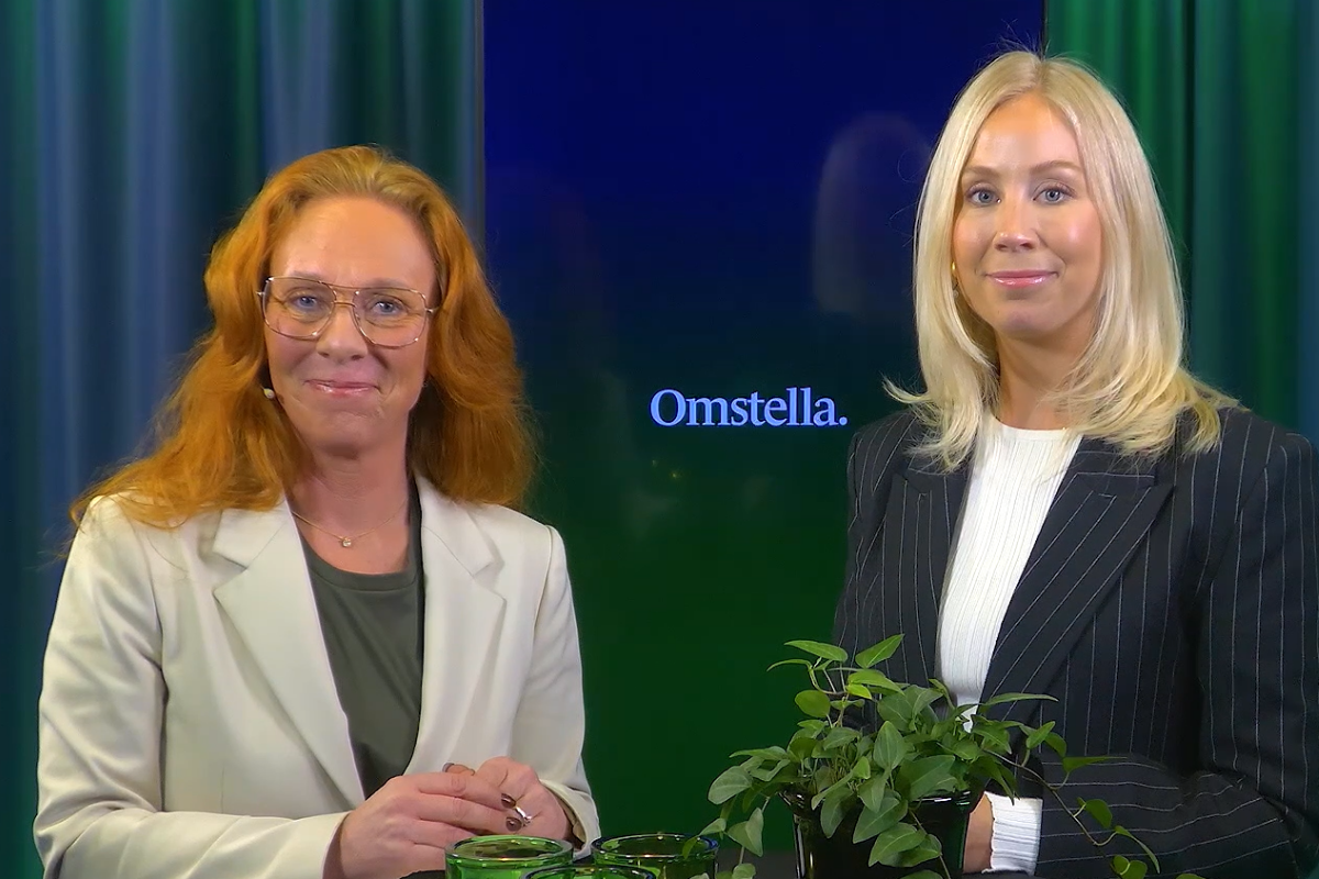 Två kvinnor står framför en grön bakgrund med en växt och texten "Omstella" synlig.